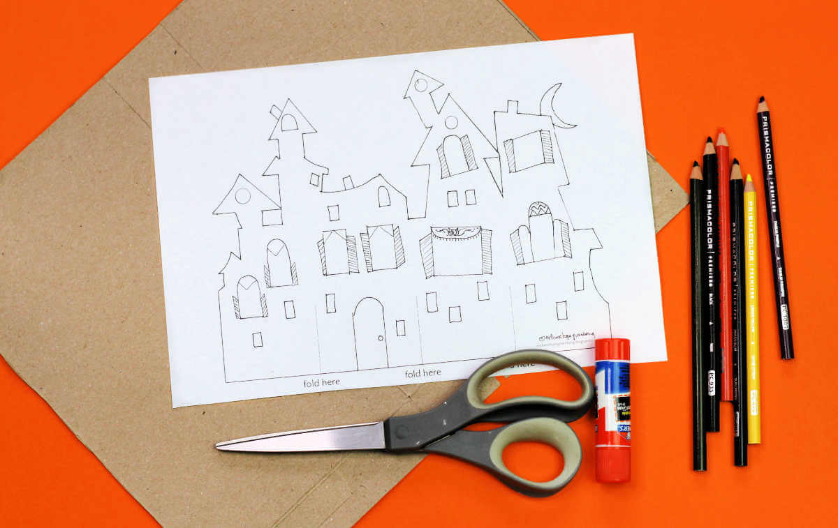 Blank haunted house template, scissors, glue stick, colored pencils and piece of cardboard