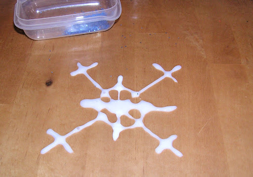 Wet glue snowflake window cling on table surface.