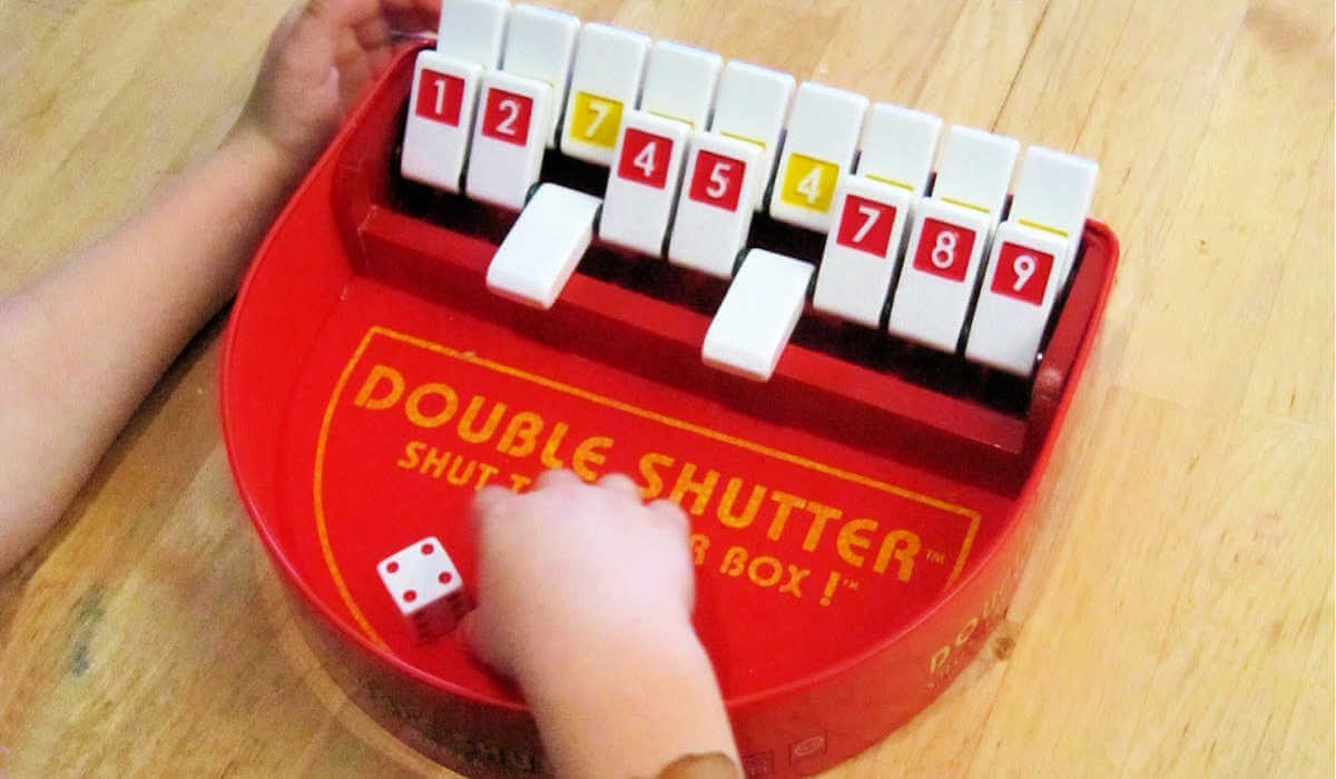 Child playing Double Shutter math game with two number tiles flipped down.
