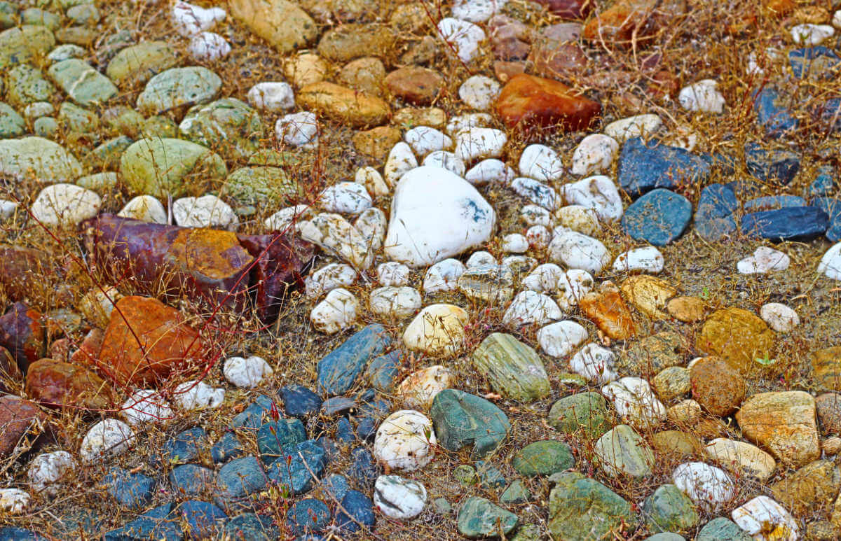 Rock mandala using colored rocks on a bed of dried grassses.