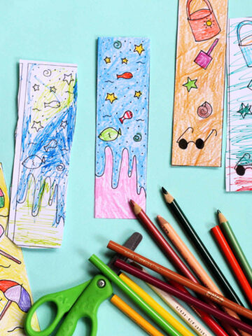 Colored summer reading bookmarks alongside kids scissors and coloring pencils.