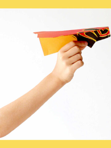 Child's hand holding paper airplane.