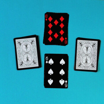 Four piles of cards laid out in cross formation. Top card is 10 of diamonds, bottom card is 6 of spades. Other two piles are face down, ready to play fraction card game.