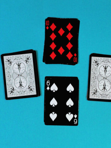 Four piles of cards laid out in cross formation. Top card is 10 of diamonds, bottom card is 6 of spades. Other two piles are face down, ready to play fraction card game.