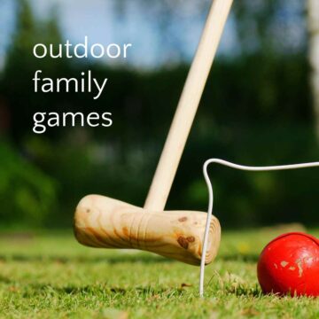 Plain wooden croquet mallet aiming at red ball under white wire wicket, with text overlay "outdoor family games."