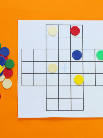 Game board for patience solitaire game with colorful tokens on the side and on the board.