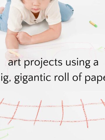 Child drawing on a big piece of paper laid out on floor.