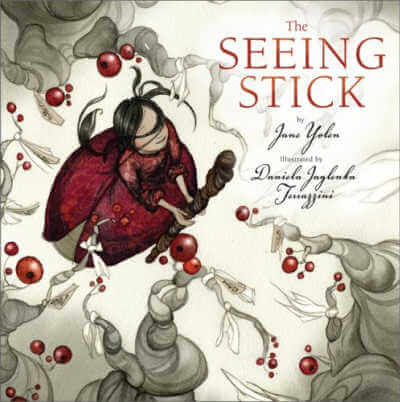 Book cover for The Seeing Stick with illustration of girl holding a large stick and standing in middle of bare trees with red berries.