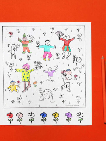 Coloring page with dancing children among flowers, partially colored in, next to several colored pencils.