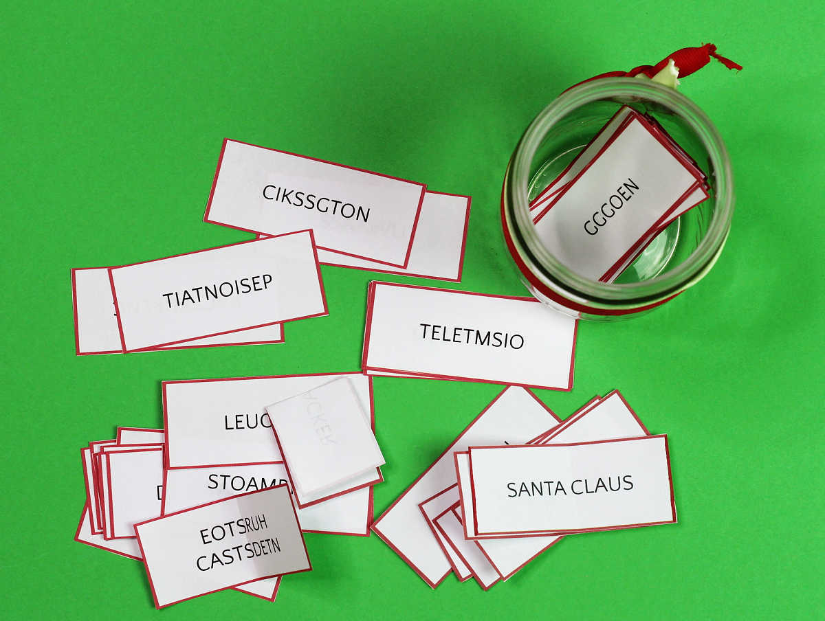 Overhead view of jar tied with ribbon holding words on small slips of paper. More words on papers scattered on green background.