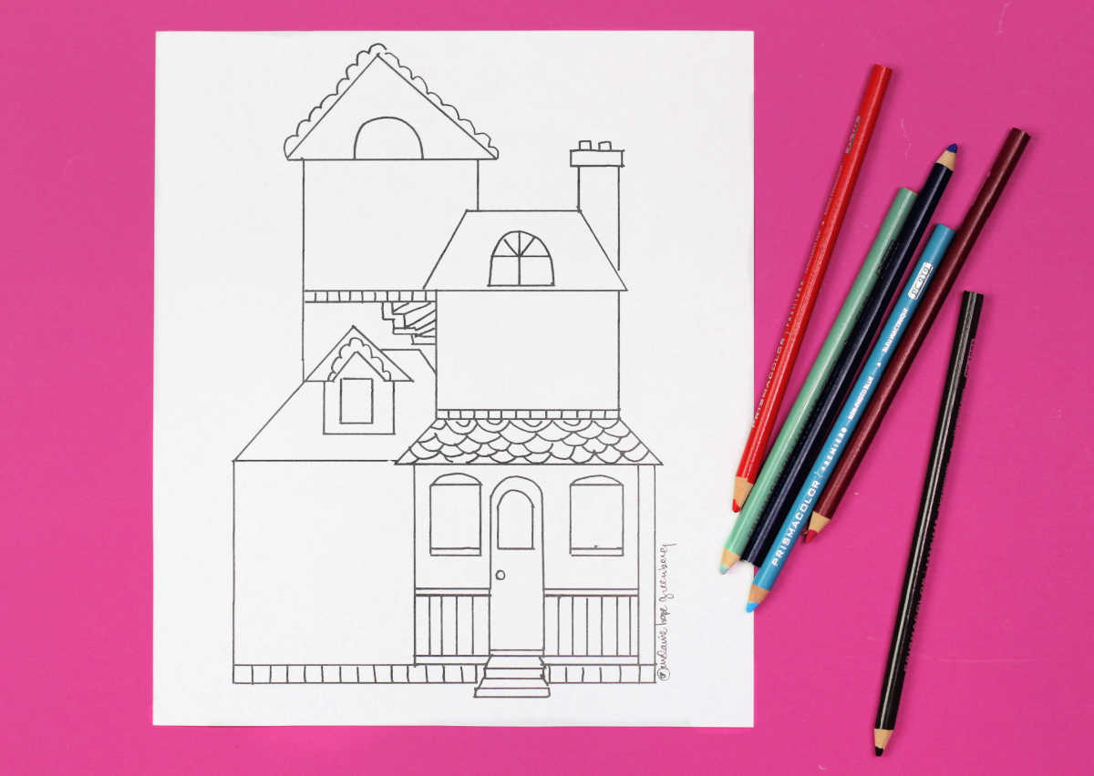 Dollhouse coloring page sitting on pink background next to colored pencils.